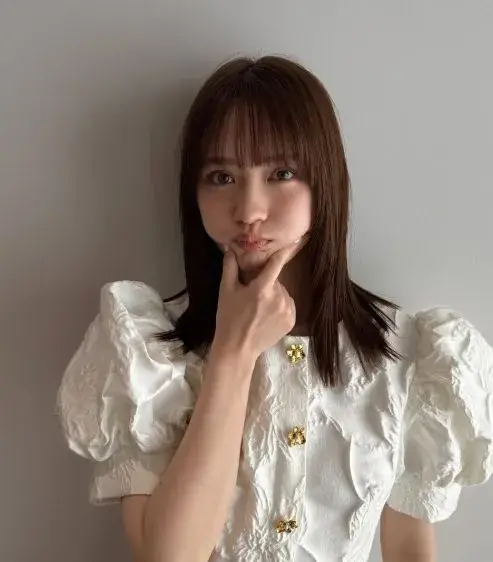 白い服を着た畑芽育さんがハーフのようなあどけなさと可愛らしさを見せているポーズ写真